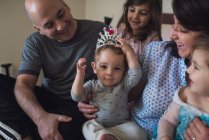 Happy family with mom, dad, 2 girls and baby wearing costume crown — Stock Photo