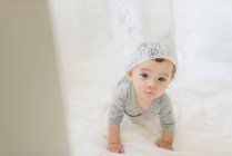 Ragazzo strisciante con tenda di pizzo bianco drappeggiato sulla testa — Foto stock