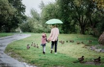 Mother and daughter walking together holding hands on a rainy day — Stock Photo