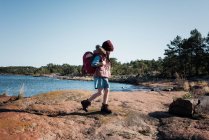Young girl hiking with a backpack on some rocks in Finland by the sea — Stock Photo