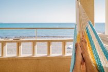 Person gestreckt auf einer Hängematte mit den Füßen nach oben, Blick auf das Meer — Stockfoto