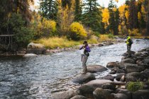 Man and woman fly fishing while standing on rocks at Roaring Fork River — Stock Photo