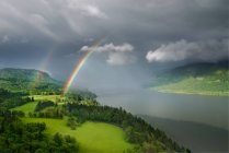 Beautiful landscape with a rainbow and a cloudy sky — Stock Photo