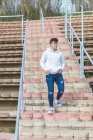 Young male teenager going down stairs hands on pocket while looking away — Stock Photo