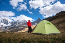 Uma mulher de pé em um acampamento de alta altitude ao lado de uma tenda em Huayhuash — Fotografia de Stock