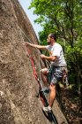 View to man rock climbing on rocky wall in the rainforest — Stock Photo