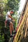 Vista al hombre escalada en roca en pared rocosa en la selva tropical - foto de stock