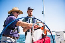 Man learning how to navigate during a family sail on sunny summer day — Stock Photo