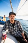 Young man enjoying summer sail race during golden hour with drink — Stock Photo