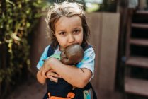 Закрыть маленькую девочку, обнимающуюся с любимым малышом на улице — стоковое фото