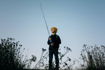 Молодий хлопчик щасливо рибалить на заході сонця один — стокове фото