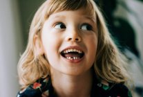 Junges Mädchen lächelt und zeigt ihren wackeligen Zahn, der glücklich aussieht — Stockfoto