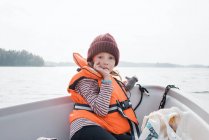 Young girl sucking her thumb sat on a fishing boat in the ocean — Stock Photo