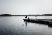 Jeune garçon pêche sur le bout d'une jetée avec son père et son ami — Photo de stock