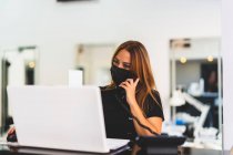 Mujer emprendedora que trabaja con su ordenador desde su negocio - foto de stock