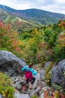 Mujer joven caminando montaña abajo en las Montañas Blancas durante el otoño. - foto de stock