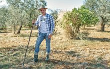 Contadino lavora con il suo rastrello per pulire la sua terra — Foto stock
