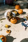 Due bambini che ritagliano zucche per Halloween sul loro patio — Foto stock