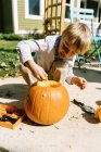 Criança esculpindo abóboras para o dia das bruxas em seu pátio — Fotografia de Stock