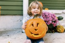 Little toddler girl holding her carved pumpkin lantern proudly — Stock Photo