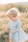 A toddler girl moving fast through a field during sunset — Stock Photo