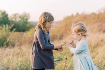 Two sisters picking flowers together during an evening walk — Stock Photo