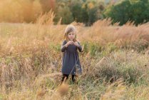 Five year old girl dispersing the seed of dried wild flowers — Stock Photo