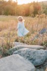 Piccola bambina che corre attraverso grandi rocce in un campo al sole — Foto stock