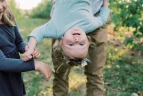 A cute toddler girl being held upside down with her sister cheering — Stock Photo