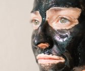 Girl with active charcoal mask relaxed in a spa — Stock Photo