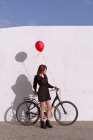 Fahrrad junge Frau trägt einen roten Gasballon — Stockfoto