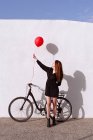 Bicicletta giovane donna che indossa un palloncino a gas rosso — Foto stock