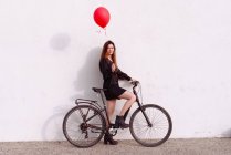 Велосипедна молода жінка в червоній газовій кулі — стокове фото