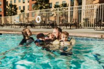 Pai e quatro crianças brincando na piscina juntos em Palm Springs — Fotografia de Stock