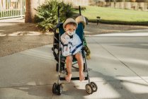 Portrait of young boy with mask on in stroller outside on vacation — Stock Photo