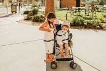Kleine Kinder mit Kinderwagen verlassen Schwimmbad mit Masken im Urlaub — Stockfoto