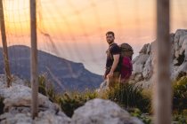 Viajante solitário fica em um ponto de vista de uma montanha durante o pôr do sol — Fotografia de Stock