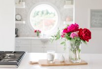 Hermosa composición de la mesa de cocina moderna con flores y taza de café sobre fondo de madera - foto de stock