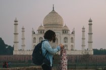 Young woman backpacker dressing her Pashmina before leaving Mehtab Bagh, with Taj Mahal in the background. — Stock Photo