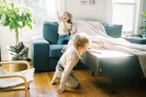 Двое детей играют вместе под одеялом в своей гостиной — стоковое фото