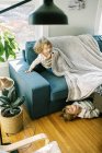 Dos niños jugando juntos bajo una manta en su sala de estar - foto de stock