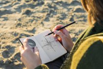 Une jeune femme dessine une boussole dans un cahier. Mode de vie, voyage — Photo de stock