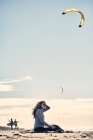 Femme s'assoit et regarde cerf-volant surfeurs d'une plage dans le sud de la Califonie — Photo de stock