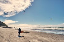 Um kite surfista caminha ao longo de uma praia no sul da Califórnia, em San Diego — Fotografia de Stock