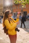 Молодая женщина турист, есть мороженое, счастливый, смеясь, яркий солнечный день, туристическая камера. — стоковое фото