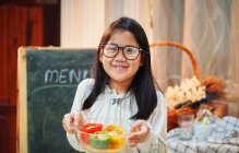 A girl showing her cooked colorful bell peppers in the glass bowl — Stock Photo
