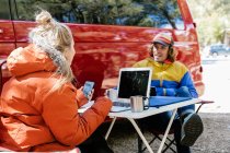 Young couple working outside their red campervan with a forest — Stock Photo