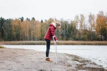 Injured woman stood at the beach with crutches looking thoughtful — Stock Photo