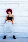 Femme aux cheveux rouges afro debout sur un mur blanc — Photo de stock