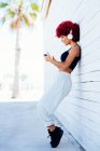 Femme aux cheveux rouges afro écoutant de la musique avec écouteurs — Photo de stock